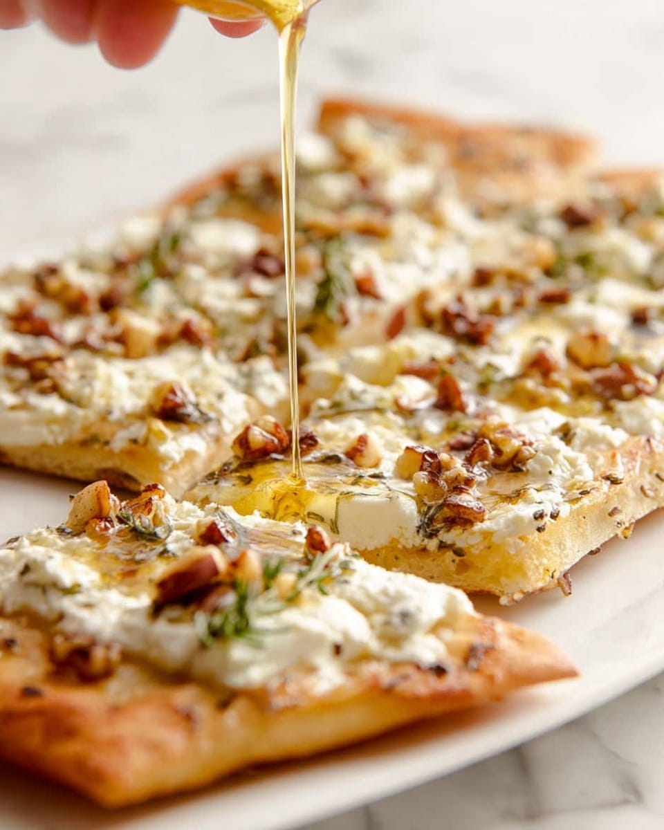 The image shows a close-up of a flatbread cut into rectangular pieces on a white plate. The flatbread has a golden brown, slightly crispy crust as the base layer. On top, there is a layer of creamy white melted cheese with a soft, smooth texture. Scattered over the cheese are small pieces of brown nuts and bits of green herbs. A thin stream of golden honey is being poured over the flatbread, adding a shiny, sticky layer across the top. The background has a white marbled texture, and a woman's hand is visible gently holding the flatbread from the side. photo taken with an iphone --ar 4:5 --v 7