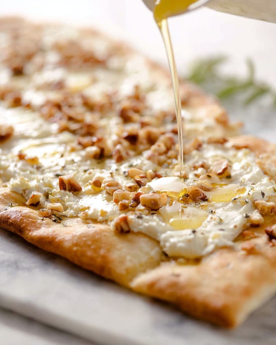 A close-up image of a rectangular flatbread pizza resting on a white marbled surface, showing a golden brown crust with a slightly thick edge. The flatbread has two main layers on top: a creamy white cheese melting evenly across the surface, and scattered bits of small, light brown nuts sprinkled generously. A thin pale yellow liquid, likely honey, is being poured onto the flatbread, creating glossy, shiny spots and slight drips on the crust. The background is softly blurred, keeping focus on the crisp texture and toppings of the flatbread. Photo taken with an iphone --ar 4:5 --v 7