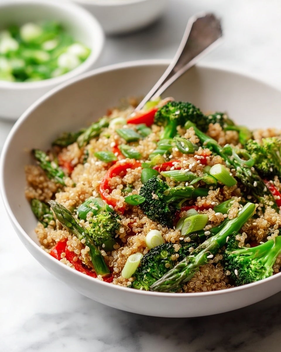 A close-up of a white bowl filled with a grain salad made of light brown quinoa as the base layer. Mixed in are bright green broccoli florets, asparagus pieces, and sliced green onions, adding fresh green colors and various textures. Small pieces of red bell pepper are scattered throughout, giving pops of red. The salad is sprinkled with tiny white sesame seeds on top. A silver fork rests inside the bowl, leaning towards the back. The bowl sits on a white marbled surface with two blurred white bowls of green vegetables in the background. photo taken with an iphone --ar 4:5 --v 7