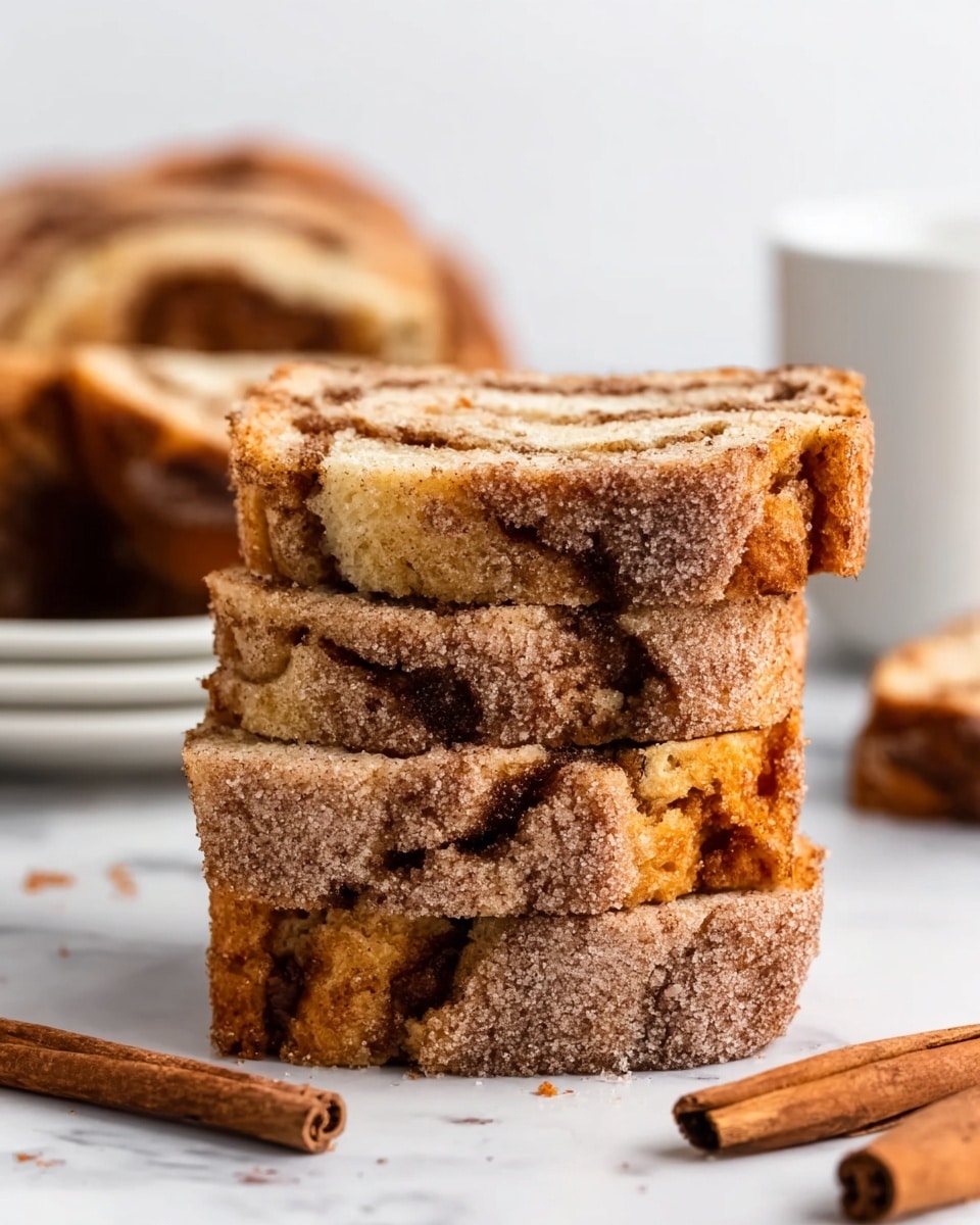The image shows a stack of four square pieces of crumb cake with a golden brown top layer covered in a thick layer of cinnamon sugar, giving it a sparkling texture. The middle layer is a moist, light yellow cake with visible pockets of cinnamon swirls that add a darker brown pattern inside. The bottom layer looks slightly firmer and more dense, similar in color to the middle layer but without the swirls. The stack sits on a white marbled surface with a cinnamon stick next to it, and blurred cake pieces on a white plate in the background. Photo taken with an iphone --ar 4:5 --v 7