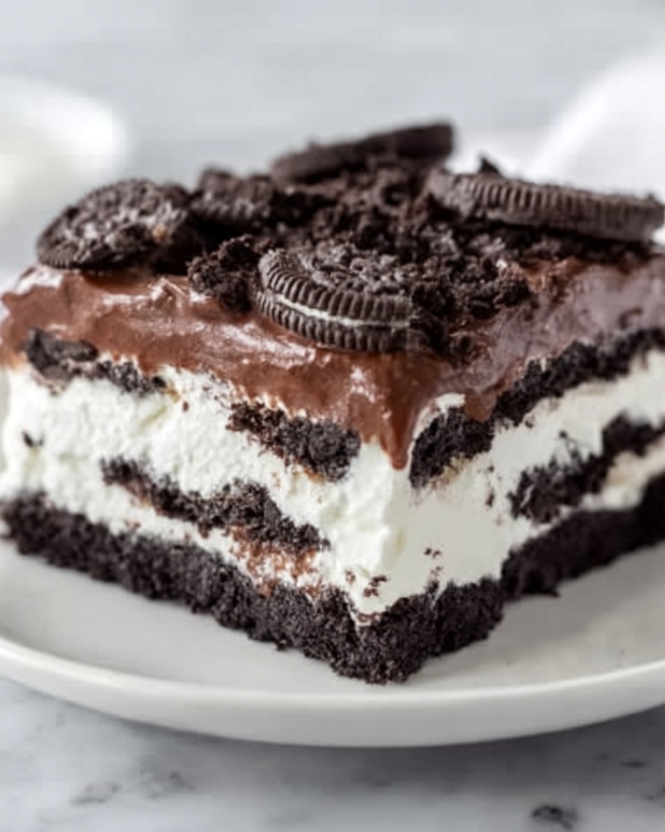 A square slice of layered dessert on a white plate, showing three distinct layers: a bottom layer of dark chocolate cookie crumbs, a middle layer of thick white cream, and a top layer of dark chocolate ganache. The dessert is topped with broken chocolate sandwich cookies scattered unevenly, adding rough texture on top. The edges of each layer are neat and clear, making the contrast between dark and white layers sharp. The plate sits on a white marbled surface. Photo taken with an iphone --ar 4:5 --v 7
