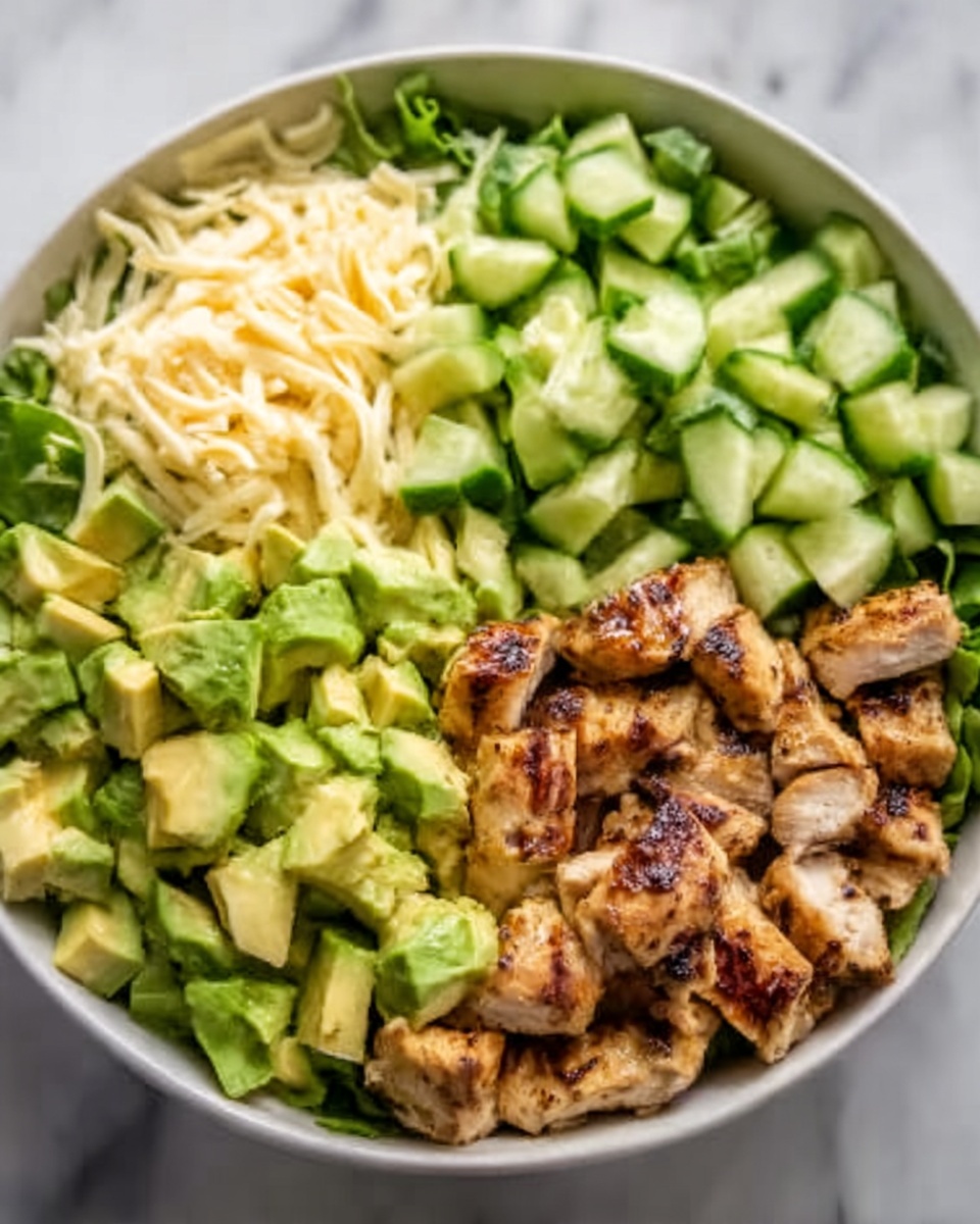 The image shows a white bowl filled with four main layers arranged side by side. On the left, diced green avocado pieces with a fresh and smooth texture. Next to it, bright green cucumber chunks with a shiny and crisp look. To the right, grilled chicken strips with dark brown char lines and a juicy, slightly shiny surface. Underneath all the layers, there is a base of rice that looks soft and slightly sticky. The bowl sits on a white marbled surface. Photo taken with an iphone --ar 4:5 --v 7