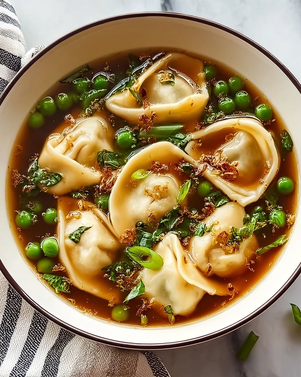 A white bowl with a black rim holds a clear brown broth soup filled with about ten plump dumplings that have smooth, light beige skin and folded edges. Bright green peas and chopped dark green leafy vegetables float among the dumplings, adding color and texture. Small bits of fried garlic or seasoning are scattered on top, creating a slight crunchy contrast. The bowl is placed on a textured cloth with a white marbled surface in the background. photo taken with an iphone --ar 4:5 --v 7