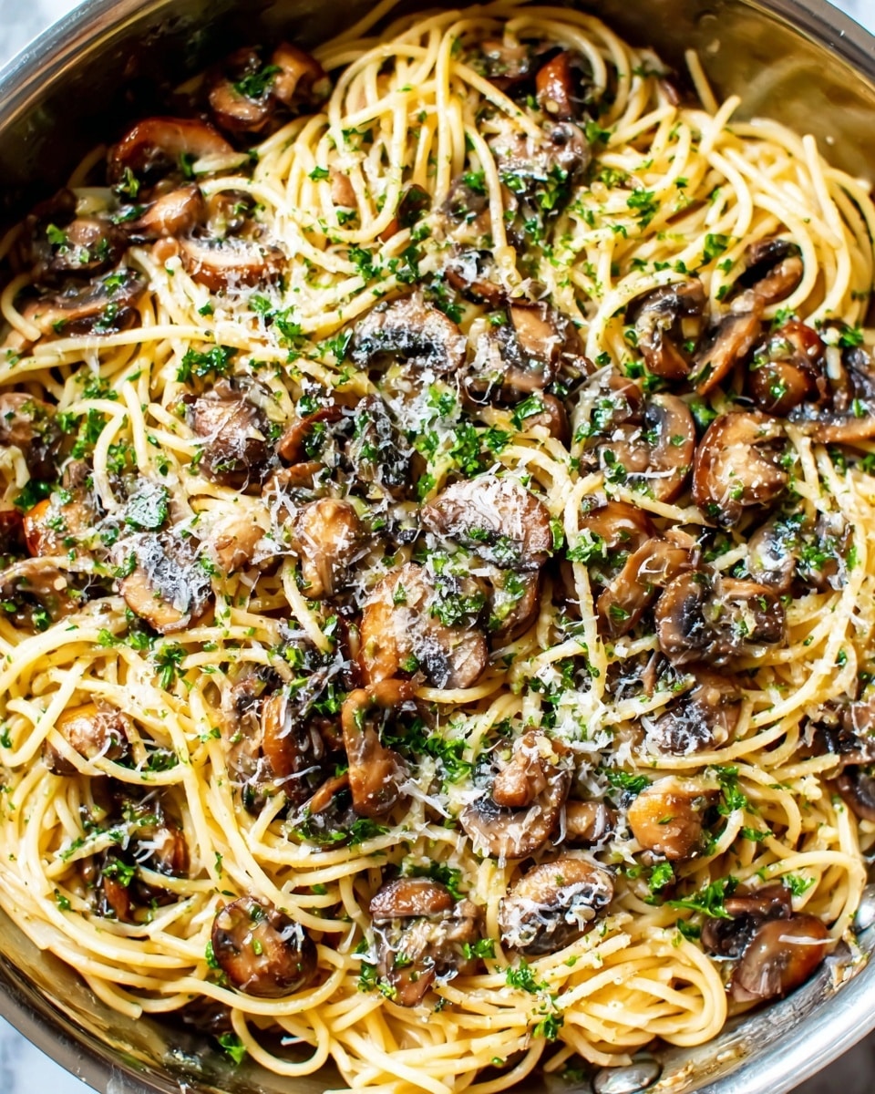 A close-up view of a pasta dish with about two layers: the first layer is light yellow spaghetti noodles spread evenly, and the second layer is a mix of sliced brown mushrooms and green parsley bits scattered on top, sprinkled with white grated cheese. The pasta is in a shiny silver pan sitting on a white marbled surface, showing a textured blend of smooth noodles and soft mushrooms. The image is bright and clear with some light reflections on the mushrooms and cheese. photo taken with an iphone --ar 4:5 --v 7